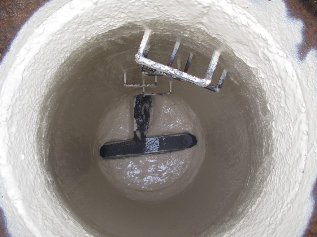 This photo shows the interior of a rehabilitated manhole after the application of a protective lining system to restore and protect the concrete surface.