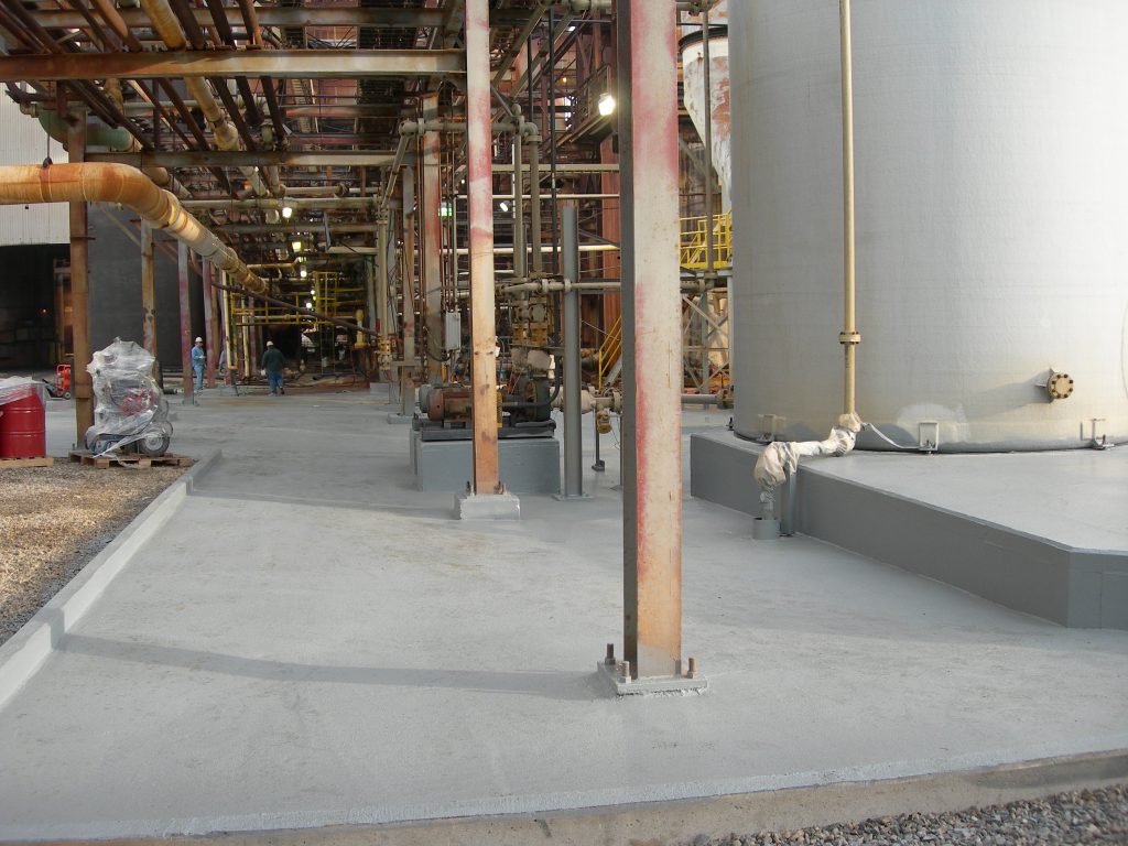 A newly coated area surrounds process equipment and storage tanks, providing a durable, chemically resistant surface designed to protect industrial infrastructure from corrosive exposure.