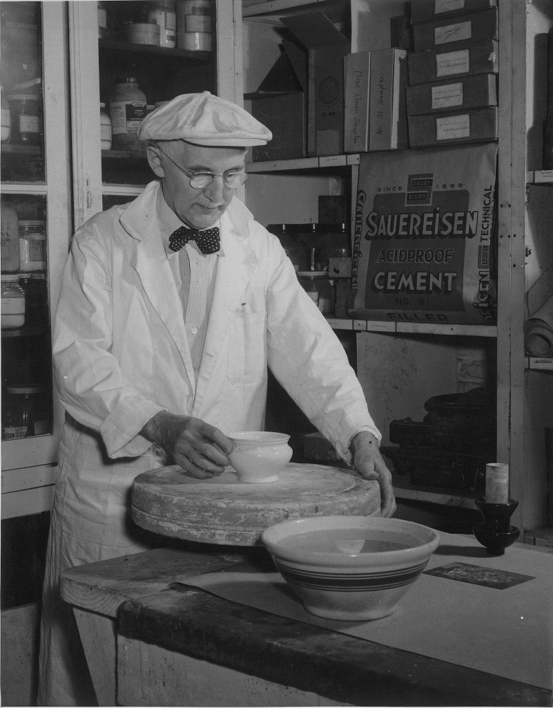 This historic photograph captures a craftsman shaping a ceramic, reflecting Sauereisen's roots in ceramic innovation. Surrounded by early Sauereisen products and laboratory materials.