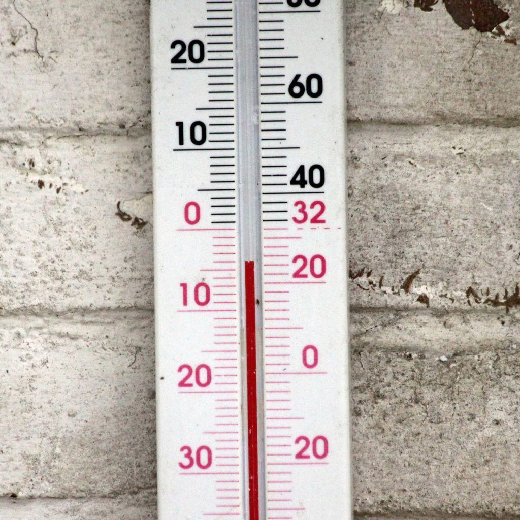 A close-up shot of a thermometer on the wall, reading just above freezing.