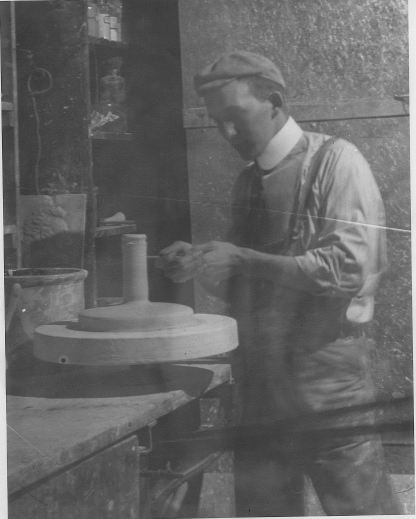 This photograph shows an early Sauereisen craftsman shaping a ceramic piece.